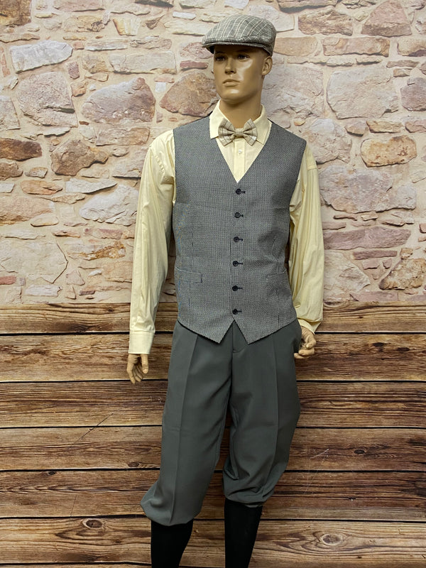 Outfit ohne Sakko: graue Knickerbocker, karierte Weste, Hemd, Schiebermütze – authentischer 20er-Jahre Vintage Look