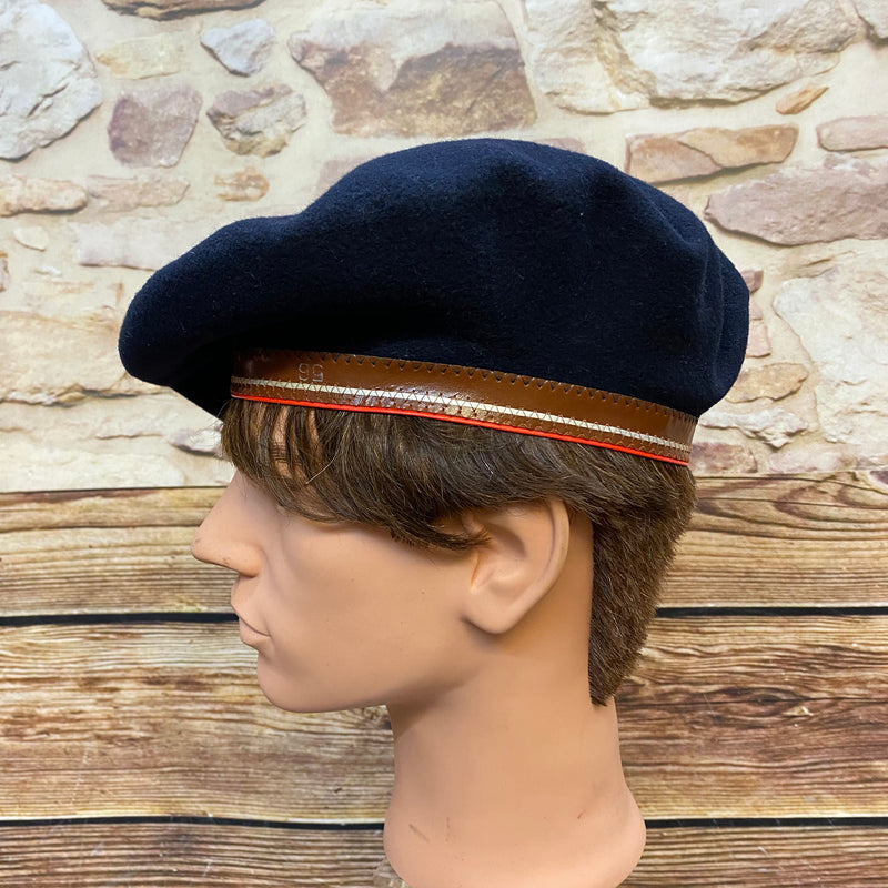„Seitliche Ansicht von dunkelblauem Vintage Barett mit braunem Rand und roter Zierlinie“