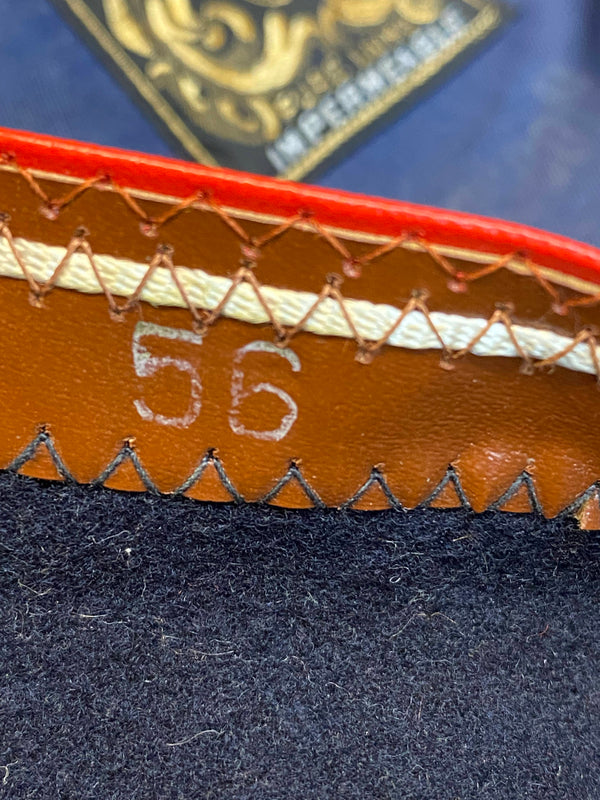 „Detailaufnahme vom Größenaufdruck 56 im dunkelblauen Vintage Barett mit braunem Innenrand“