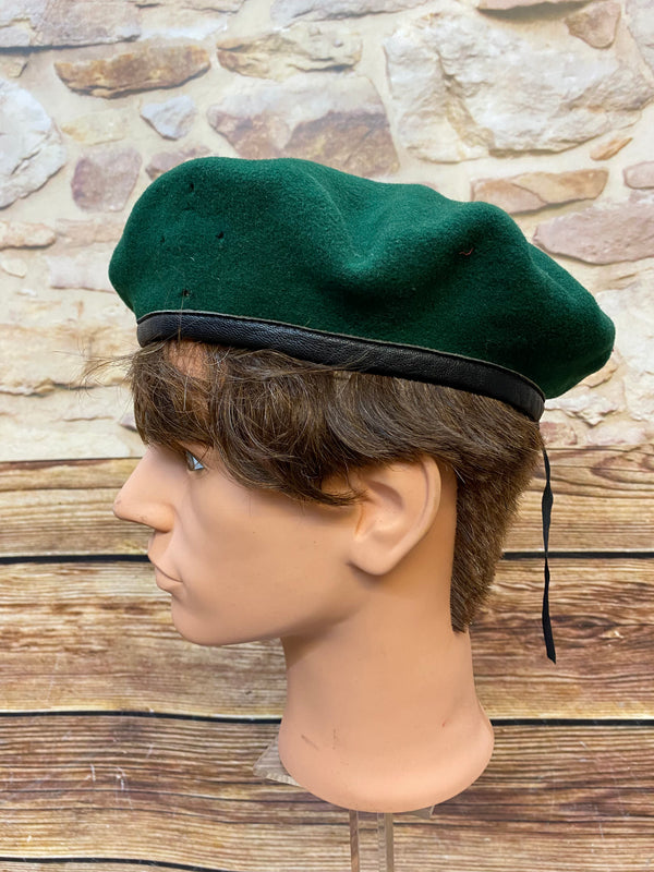 „Seitliche Ansicht von grünem Vintage Uniform-Barett mit schwarzem Rand und Zugband“