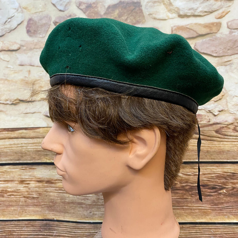 „Seitliche Ansicht von grünem Vintage Uniform-Barett mit schwarzem Rand und Zugband“
