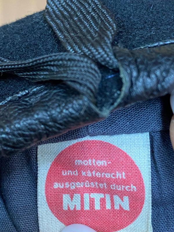 „Detailaufnahme vom Etikett 100 Prozent Wolle in schwarzem Vintage Uniform-Barett“
