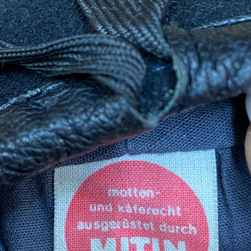 „Detailaufnahme vom Etikett 100 Prozent Wolle in schwarzem Vintage Uniform-Barett“