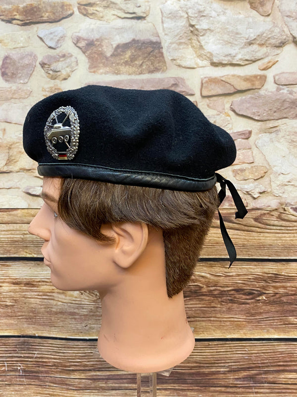 „Seitliche Ansicht von schwarzem Vintage Uniform-Barett mit Abzeichen, schwarzem Rand und Zugband“