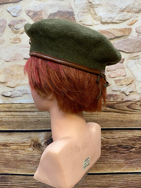 „Seitliche Ansicht von grünem Vintage Uniform-Barett mit braunem Rand und Zugband“