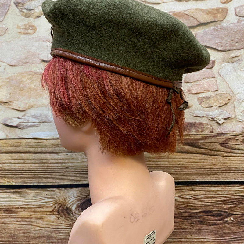 „Seitliche Ansicht von grünem Vintage Uniform-Barett mit braunem Rand und Zugband“