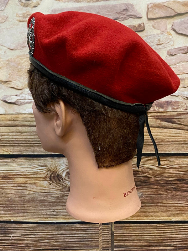 „Seitliche Ansicht von rotem Vintage Uniform-Barett mit schwarzem Rand und Zugband“