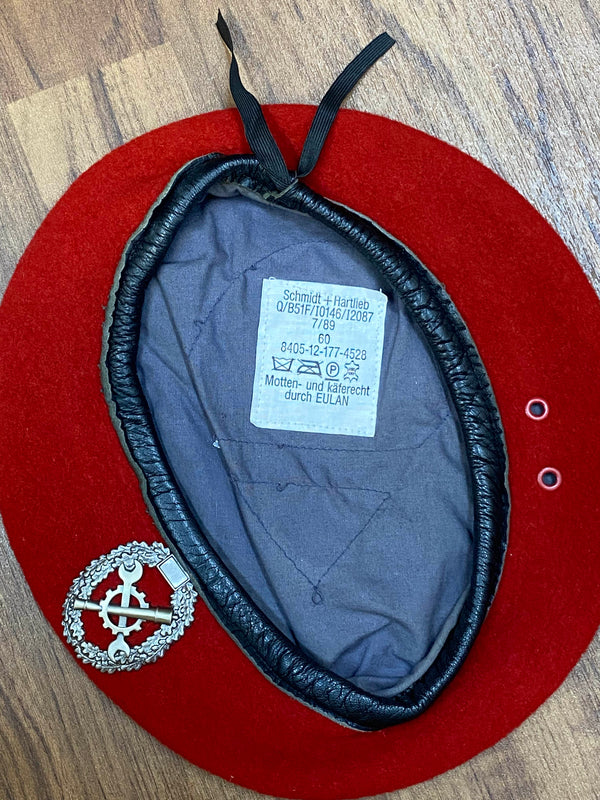 „Innenansicht eines roten Vintage Uniform-Baretts Größe 60 mit grauem Futter, Etikett und Metallabzeichen“