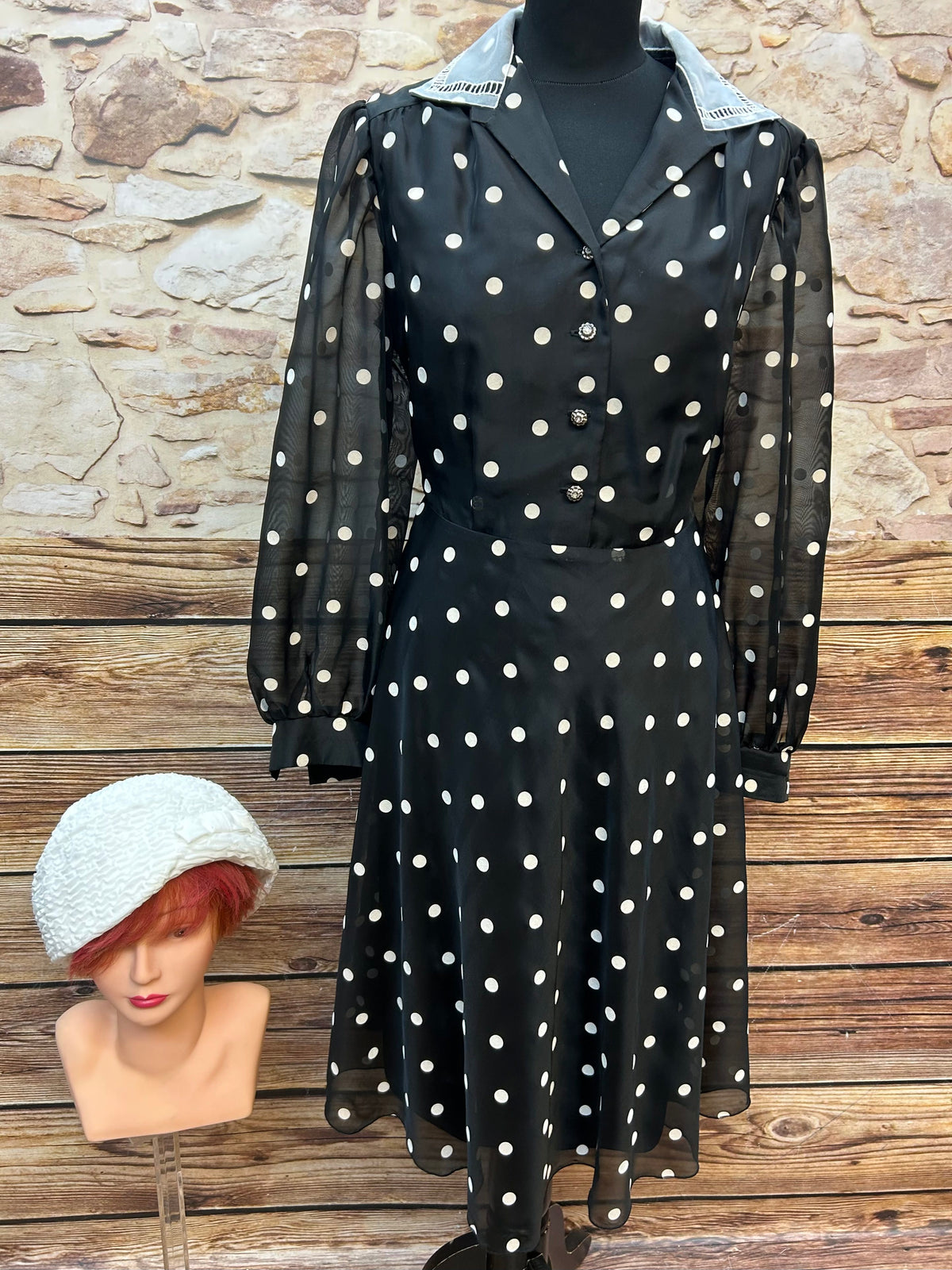 Vintage schwarzes Chiffonkleid mit weißen Tupfen, transparenten Puffärmeln und Hemdblusenkragen, dazu cremeweißer Cloche-Hut