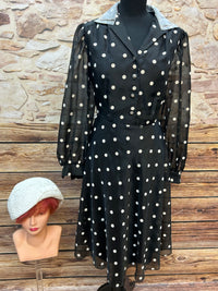 Vintage schwarzes Chiffonkleid mit weißen Tupfen, transparenten Puffärmeln und Hemdblusenkragen, dazu cremeweißer Cloche-Hut