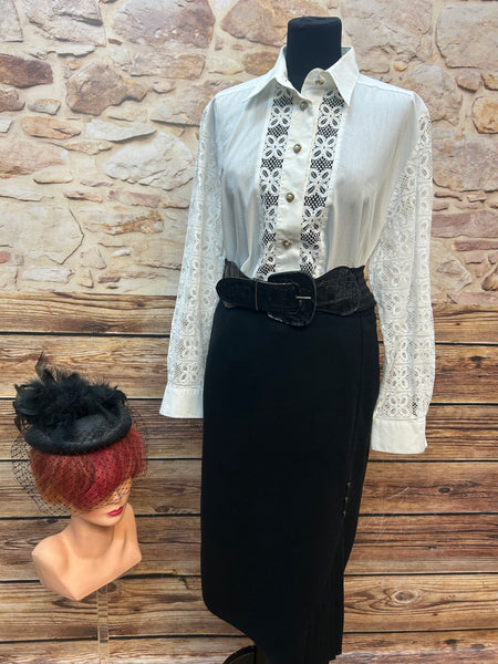 Vintage Damenkostüm Größe 44: cremefarbene Spitzenbluse mit Perlmuttknöpfen, schwarzer Bleistiftrock mit Falteneinsatz, Stretch-Gürtel und schwarzer Filzhut.