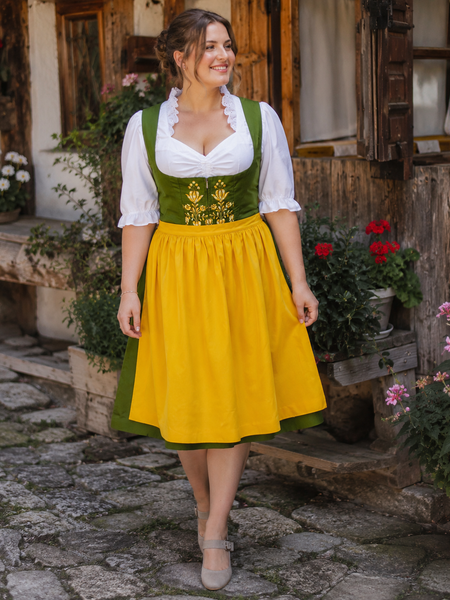 Vintage Dirndl Damen in Grün mit gelber Schürze und weißer Bluse, traditionelles Trachtenkleid für Oktoberfest und Volksfest, am Modell in ländlicher Umgebung, KI-generiert.