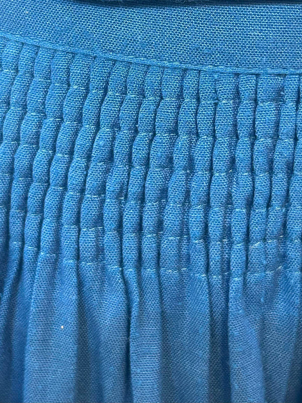 „Detail des gesmokten Bundes einer blauen Trachtenschürze aus Leinenmix“