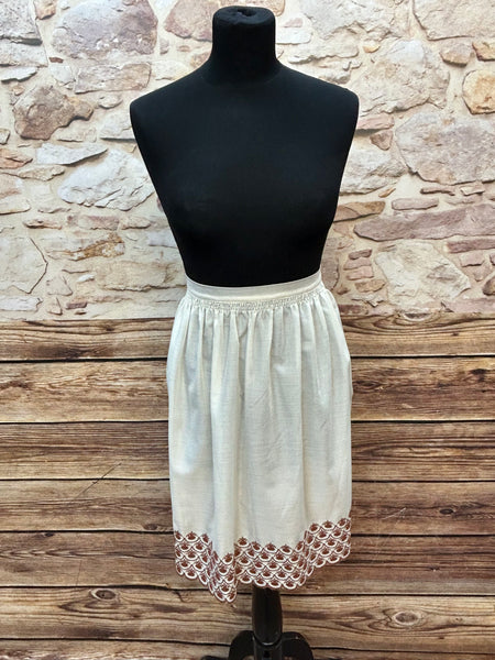 „Ecrufarbene Vintage-Dirndlschürze mit brauner Bordürenstickerei auf Puppe, Länge 55 cm“