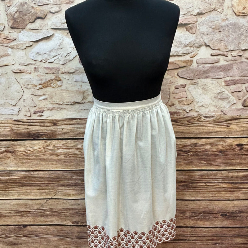 „Ecrufarbene Vintage-Dirndlschürze mit brauner Bordürenstickerei auf Puppe, Länge 55 cm“