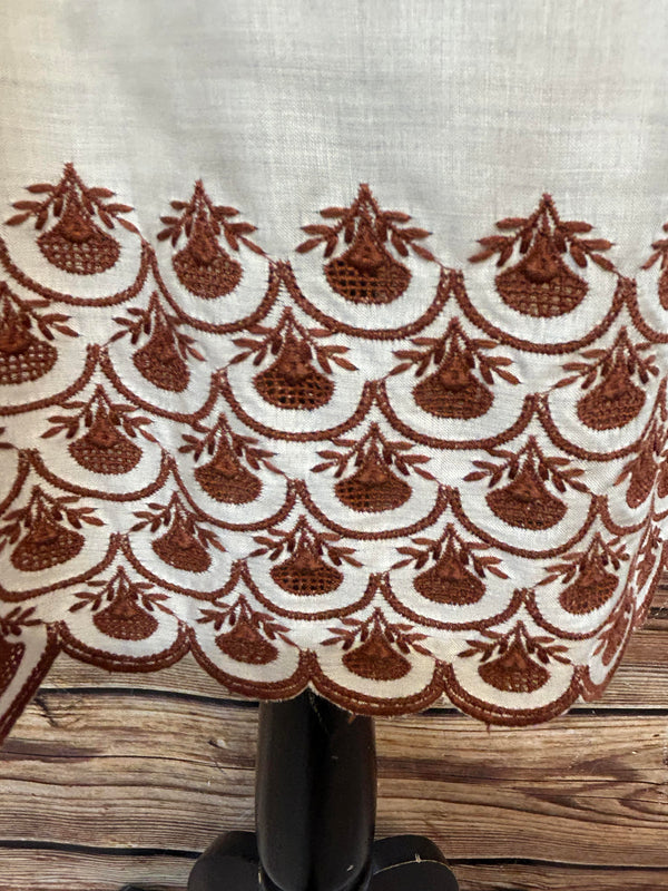 „Nahaufnahme Bund und Stickerei der ecrufarbenen Dirndlschürze mit brauner Bordüre“