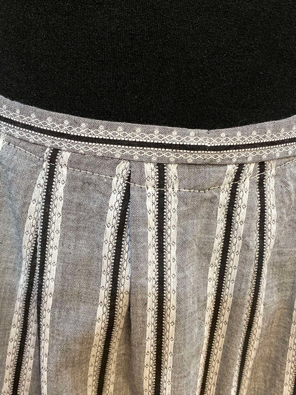 „Nahaufnahme Bund und Falten der grauen gestreiften Vintage Dirndl-Schürze“