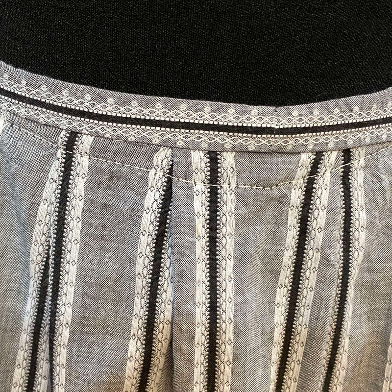 „Nahaufnahme Bund und Falten der grauen gestreiften Vintage Dirndl-Schürze“