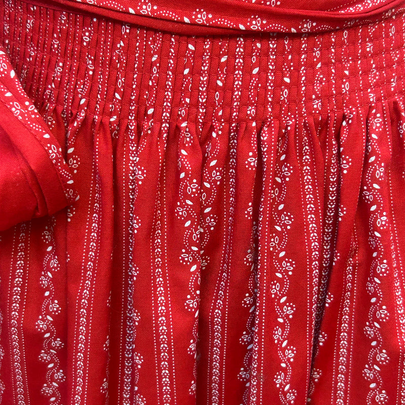 „Detail der gerafften Passe einer roten Dirndl-Schürze mit Muster“
