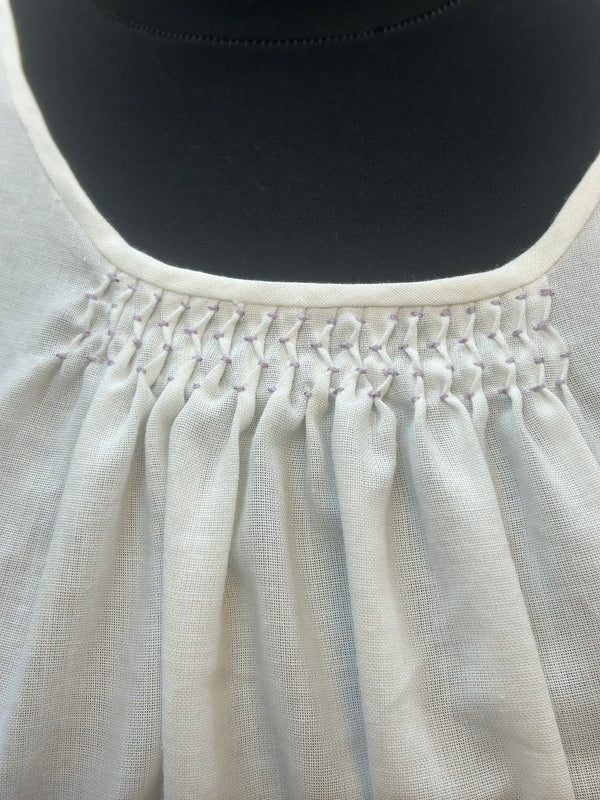 „Detailaufnahme des handgesmockten Ausschnitts einer weißen Vintage-Dirndlbluse“