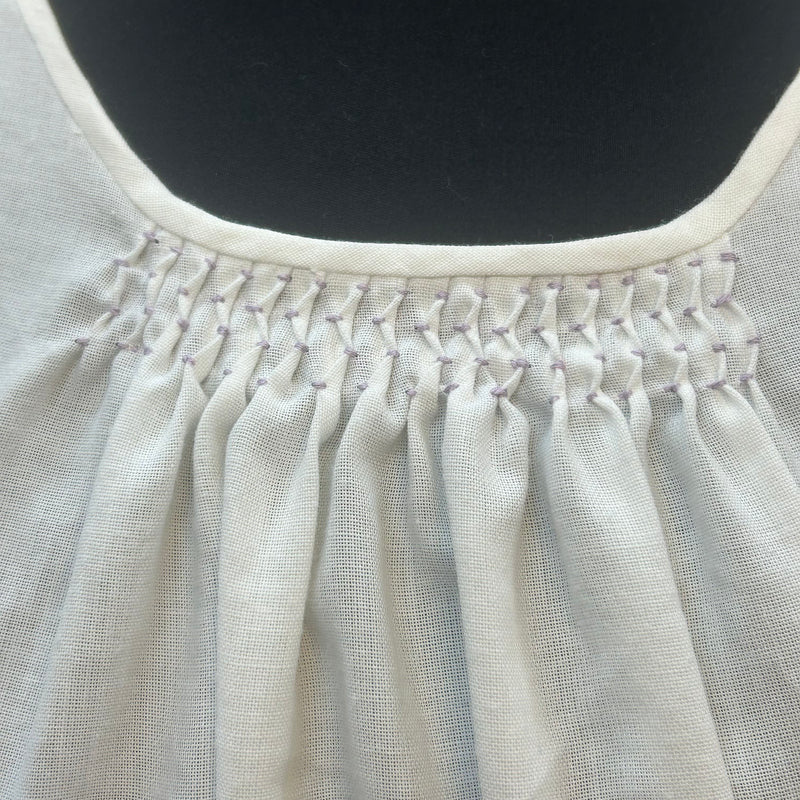 „Detailaufnahme des handgesmockten Ausschnitts einer weißen Vintage-Dirndlbluse“