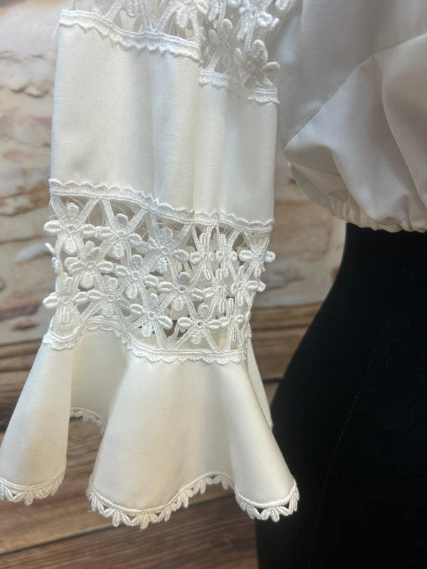 „Detailaufnahme der Spitzen-Volantärmel einer weißen Vintage-Dirndlbluse“