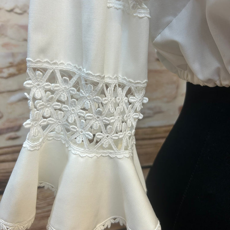 „Detailaufnahme der Spitzen-Volantärmel einer weißen Vintage-Dirndlbluse“