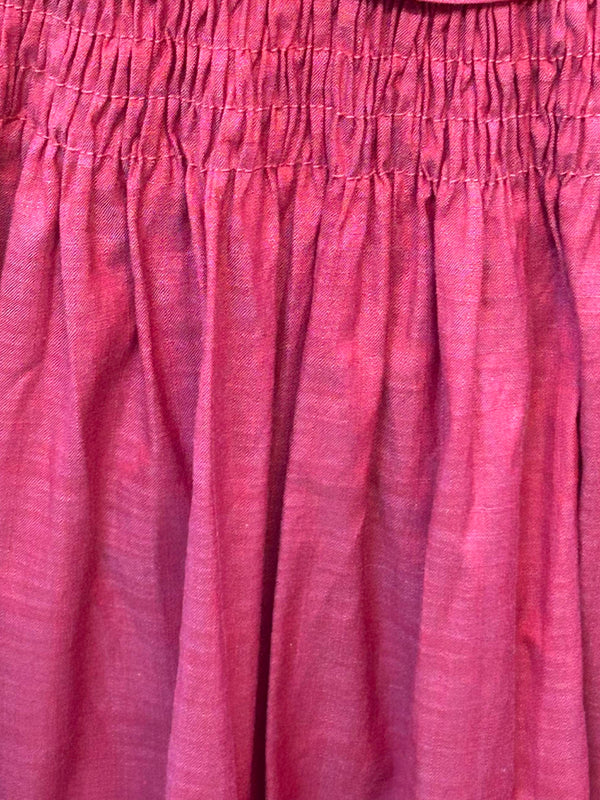„Detail Smockbund der himbeerroten Vintage-Dirndl-Schürze aus Baumwolle“