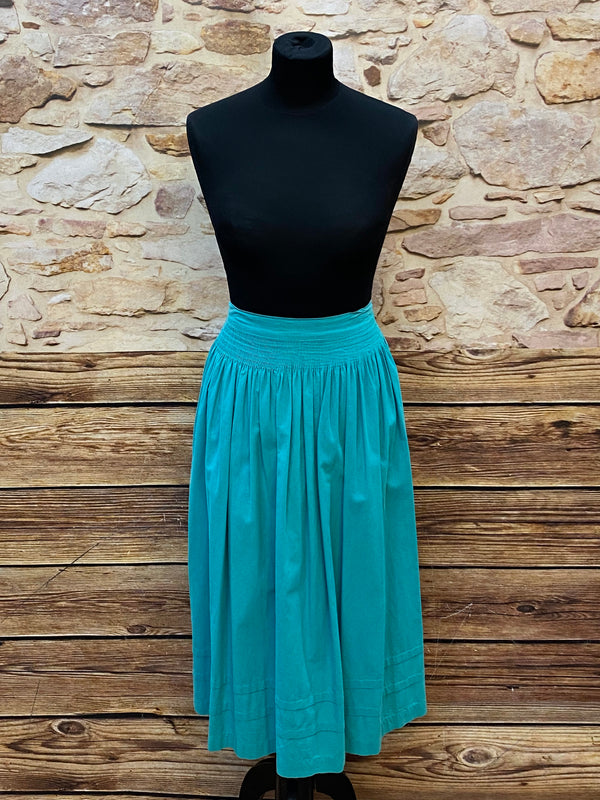 „Lange Vintage-Dirndlschürze in Petrol/Türkis mit Smokbund.“