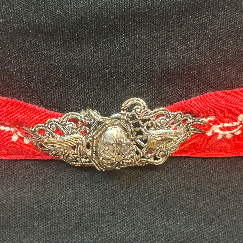 „Detailansicht Bund der roten Dirndl-Schürze mit silberfarbener Trachten-Schließe“