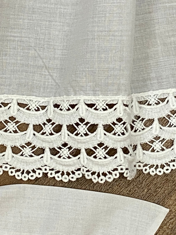 „Detail der Spitzenborte einer weißen Vintage-Dirndlschürze aus Baumwoll-Mischgewebe“