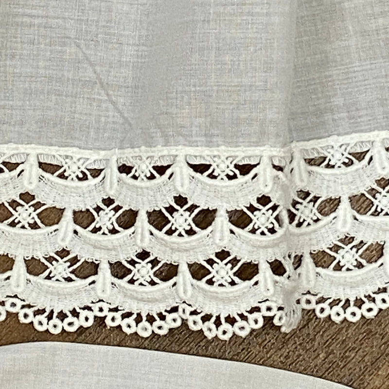 „Detail der Spitzenborte einer weißen Vintage-Dirndlschürze aus Baumwoll-Mischgewebe“