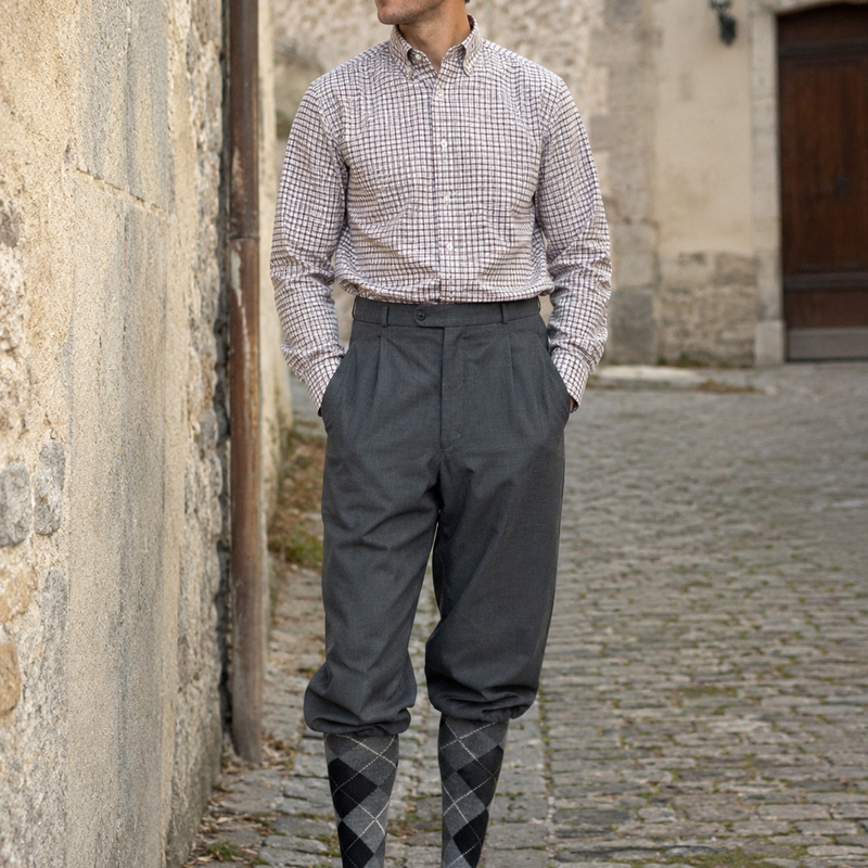 KI-generiertes Bild eines Vintage-Herren mit grauer Knickerbocker, kariertem Hemd, Rautenstrümpfen und Schiebermütze in einer historischen Altstadtgasse.