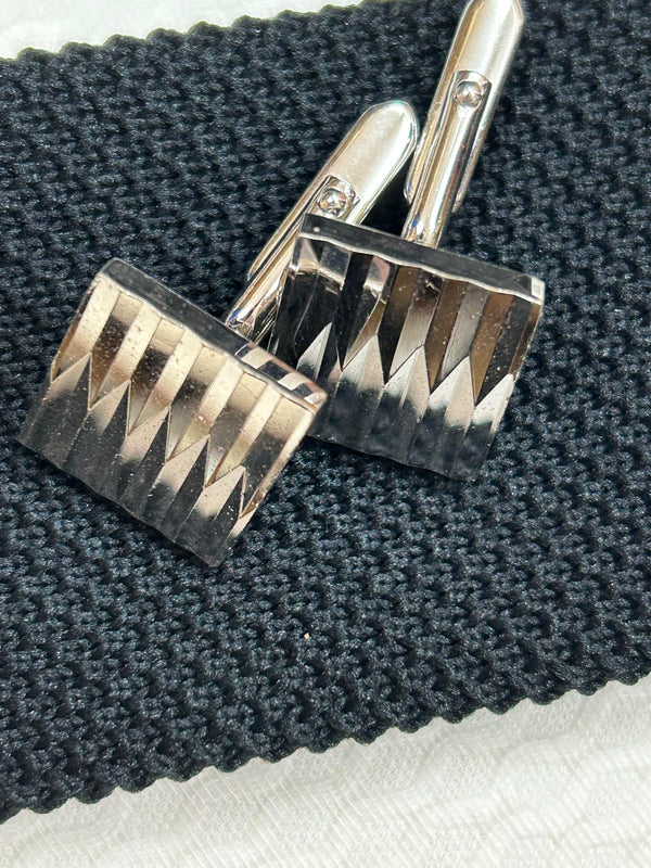 Silberne Vintage-Manschettenknöpfe auf schwarzer Krawatte im Detail