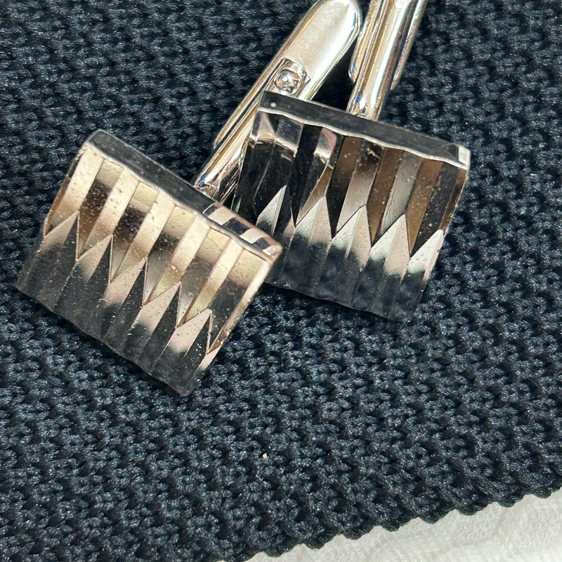 Silberne Vintage-Manschettenknöpfe auf schwarzer Krawatte im Detail
