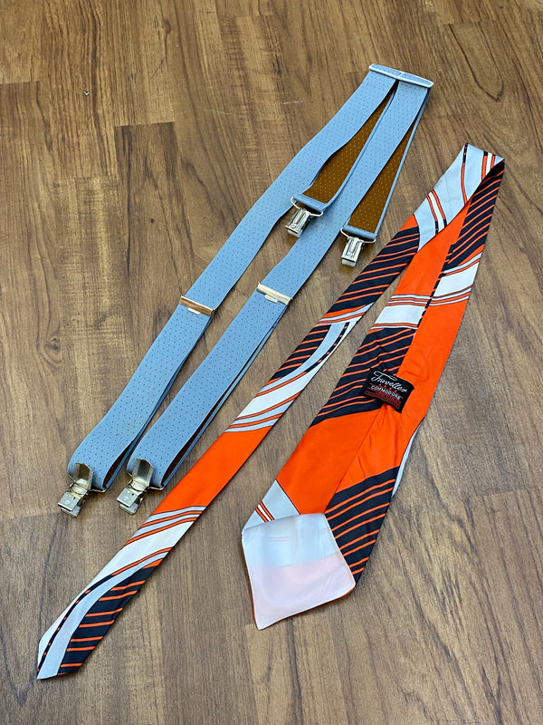 Vintage Accessoires für Herren – graue Hosenträger und rot-grau gestreifte Krawatte im Set, auf Holzuntergrund präsentiert.