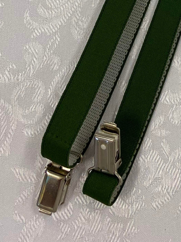 „Detailaufnahme grüne Hosenträger mit Metallclips und elastischem Band“