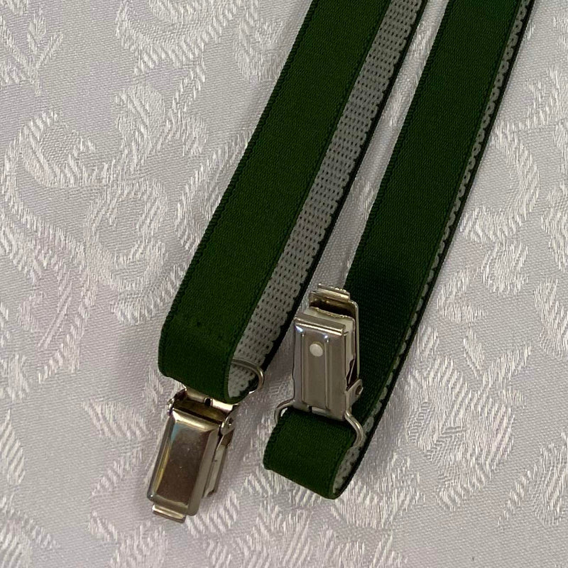„Detailaufnahme grüne Hosenträger mit Metallclips und elastischem Band“