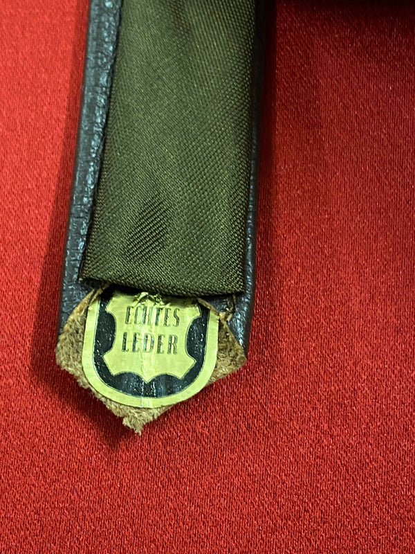 „Vintage Lederkrawatte dunkelbraun aus echtem Leder auf rotem Hintergrund“
