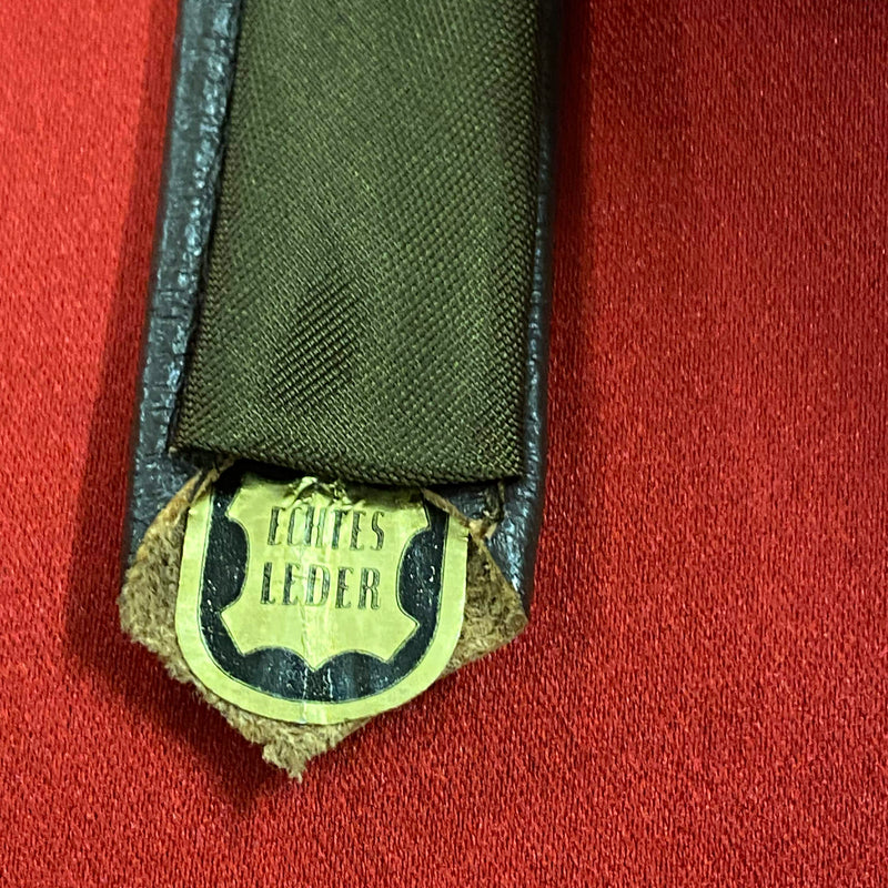 „Vintage Lederkrawatte dunkelbraun aus echtem Leder auf rotem Hintergrund“