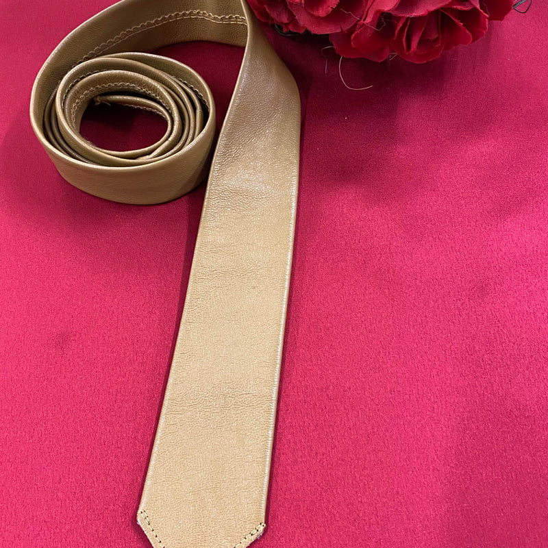 „Beige Lederkrawatte Vintage gerollt auf rotem Hintergrund“