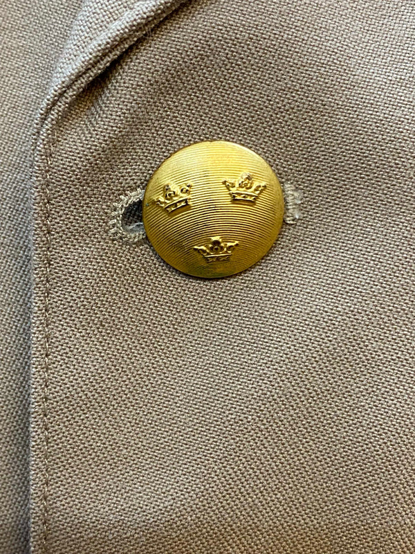 Detailaufnahme goldfarbener Knopf mit schwedischem Drei-Kronen-Wappen
