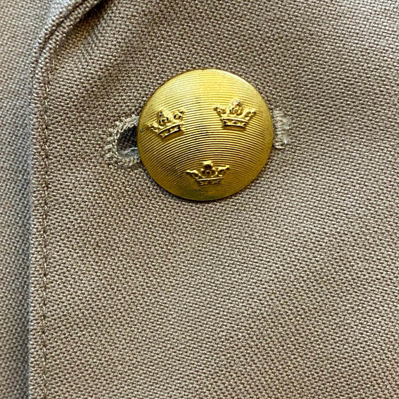 Detailaufnahme goldfarbener Knopf mit schwedischem Drei-Kronen-Wappen
