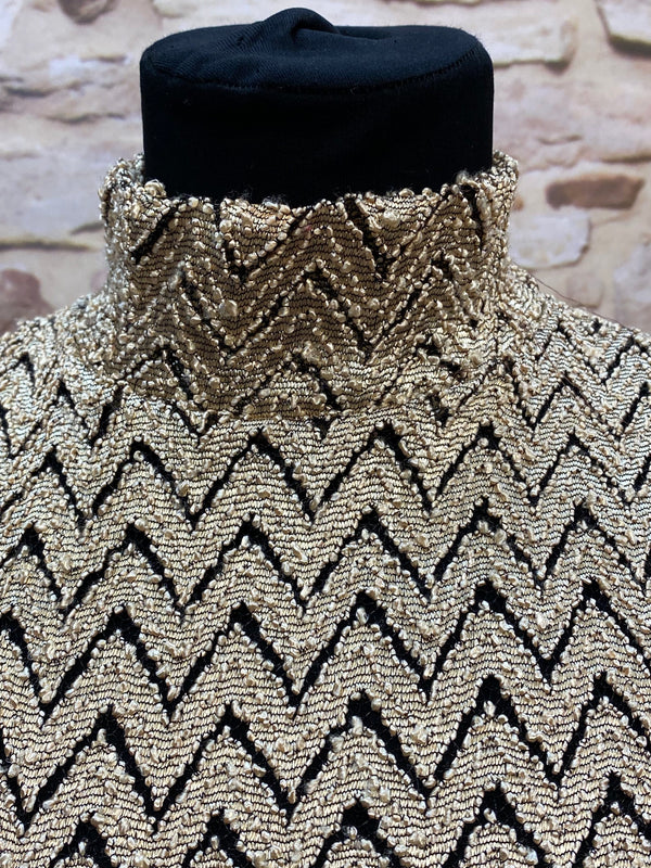 „Detailaufnahme vom gold-schwarzen Vintage Oberteil mit Zickzack-Muster und Stehkragen“