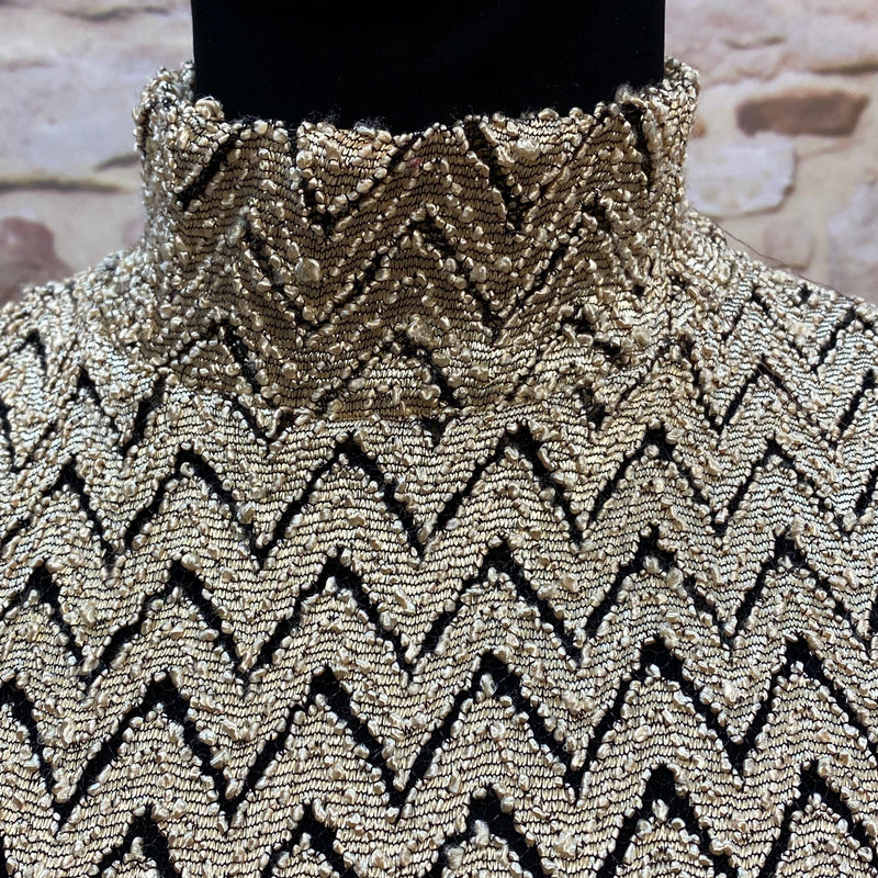 „Detailaufnahme vom gold-schwarzen Vintage Oberteil mit Zickzack-Muster und Stehkragen“