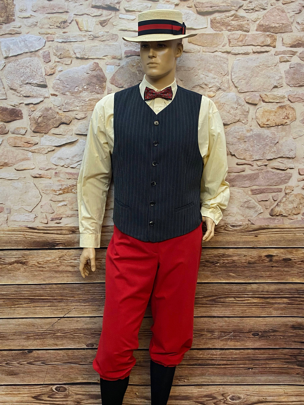 Vintage 1920er Oldtimer-Herren-Outfit am Schaufenster: Hemd, Nadelstreifen-Weste, rote Knickerbocker-Hose, Strohhut und Fliege.