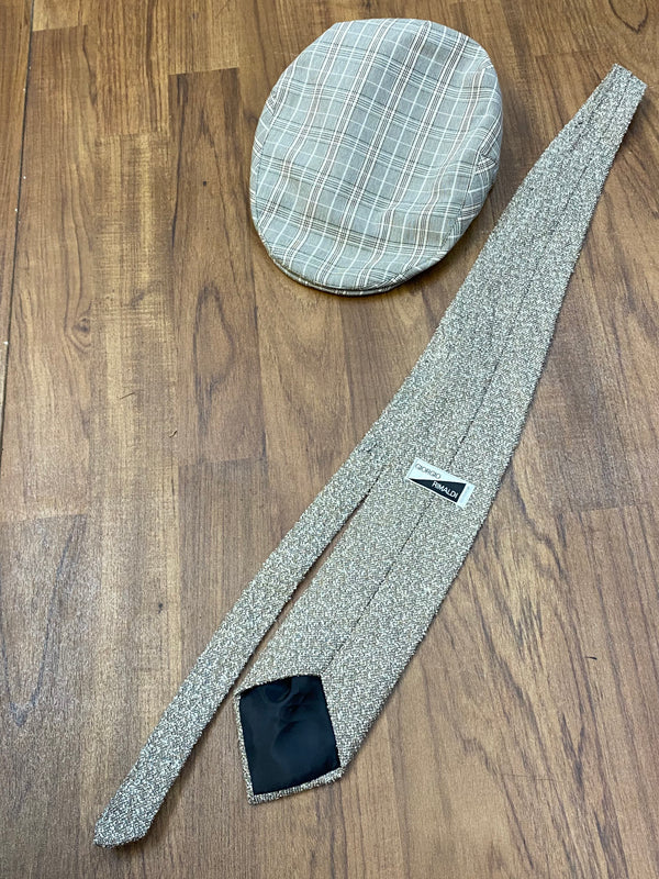 Vintage Accessoires: karierte Schiebermütze und gemusterte Krawatte auf Holzuntergrund