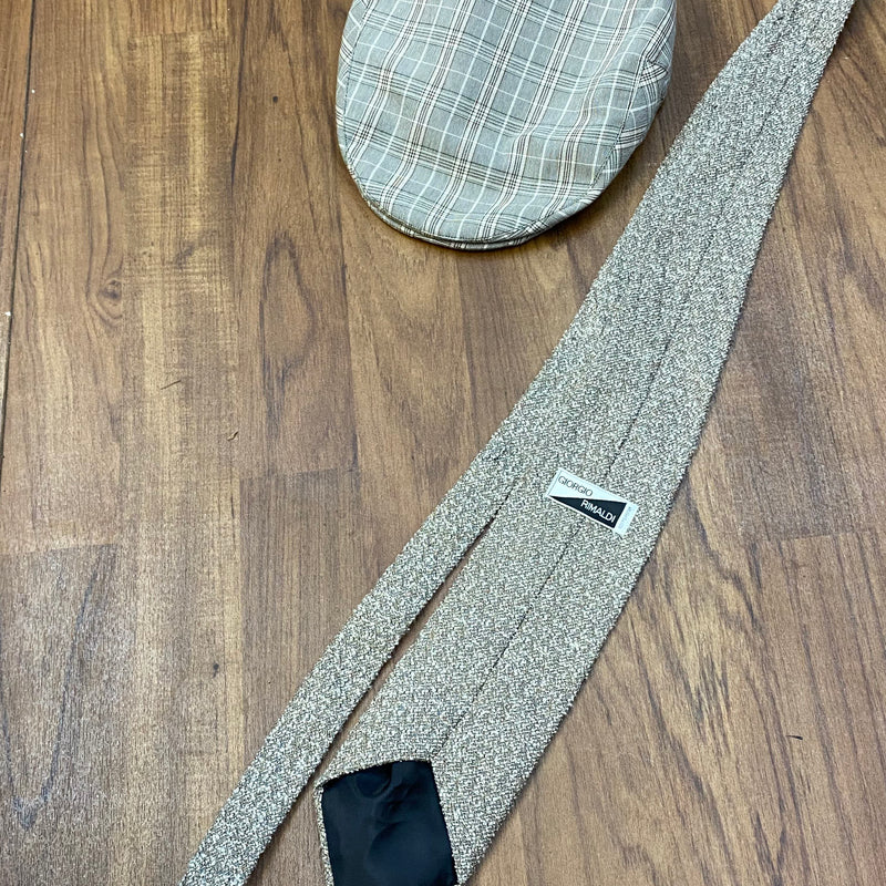 Vintage Accessoires: karierte Schiebermütze und gemusterte Krawatte auf Holzuntergrund