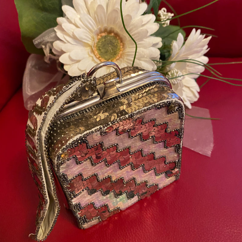 Quadratische Vintage-Minaudière (10 × 10 × 5 cm) in Zick-Zack-Pailletten aus Pastell- und Silber-Tönen, silberner Metallbügel, kurzer Handgelenkriemen, 1920er-/30er-Jahre.