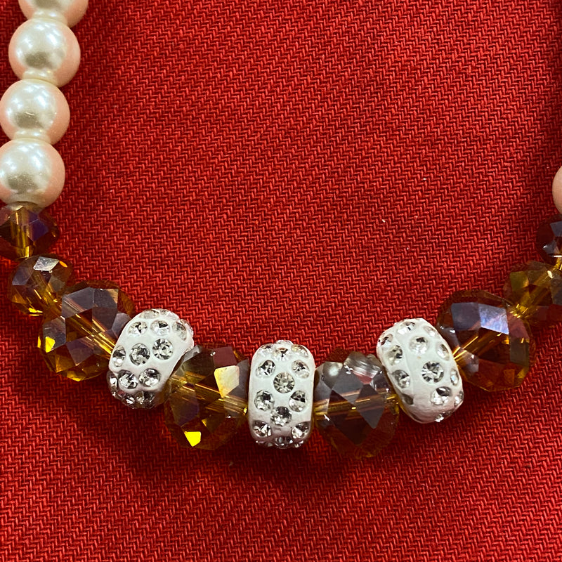 Vintage-Perlenkette, 55 cm lang, mit cremeweißen Perlen, funkelnden Kristallakzenten und weißen Strass-Zwischenelementen auf rotem Hintergrund.